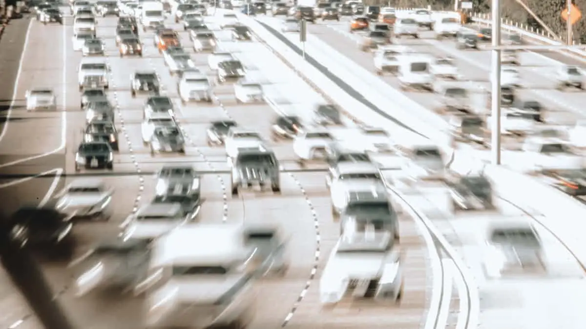 Blurred image of a busy highway with cars moving quickly in multiple lanes